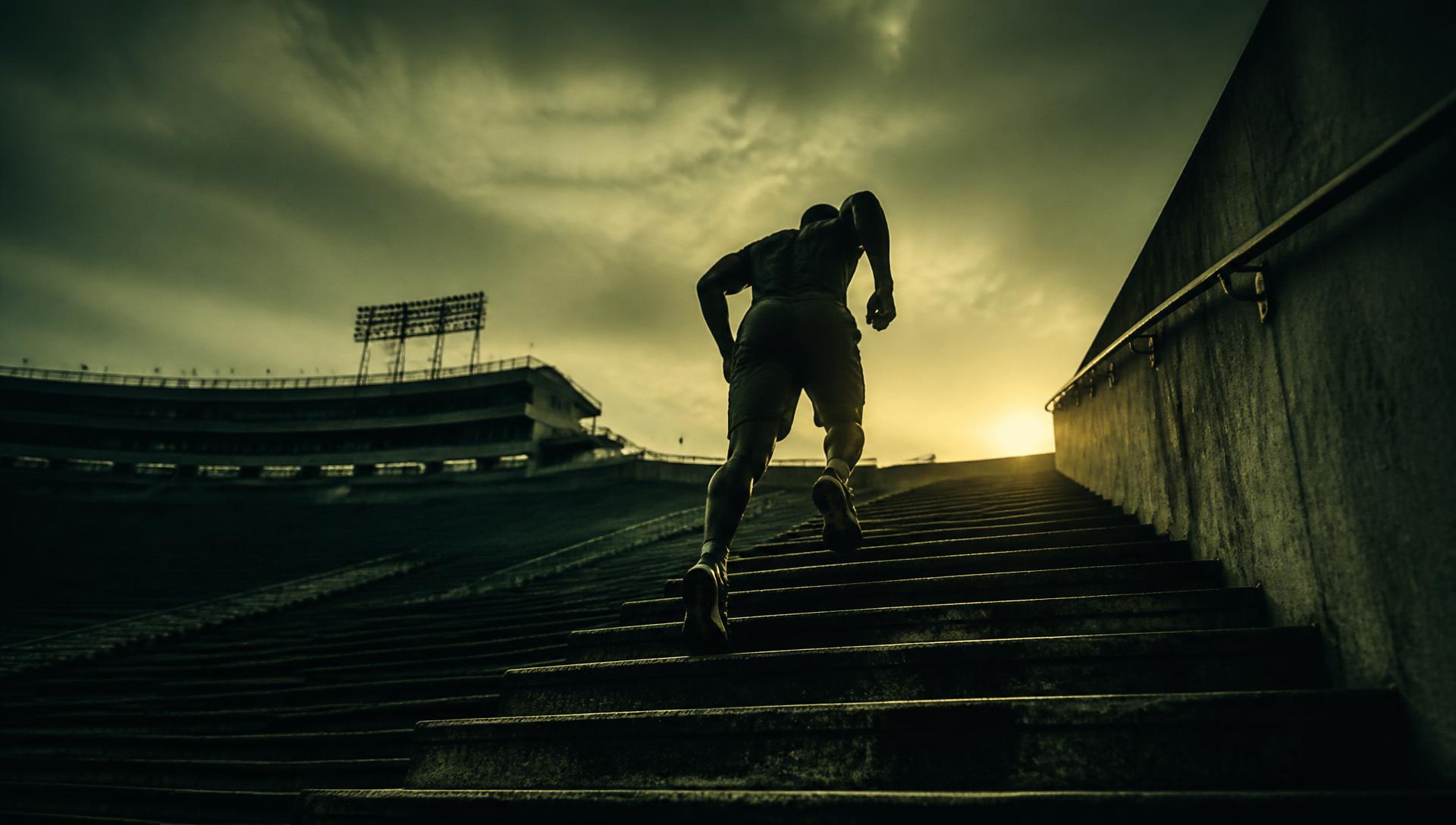 Athlete running up stadium stairs at sunrise
